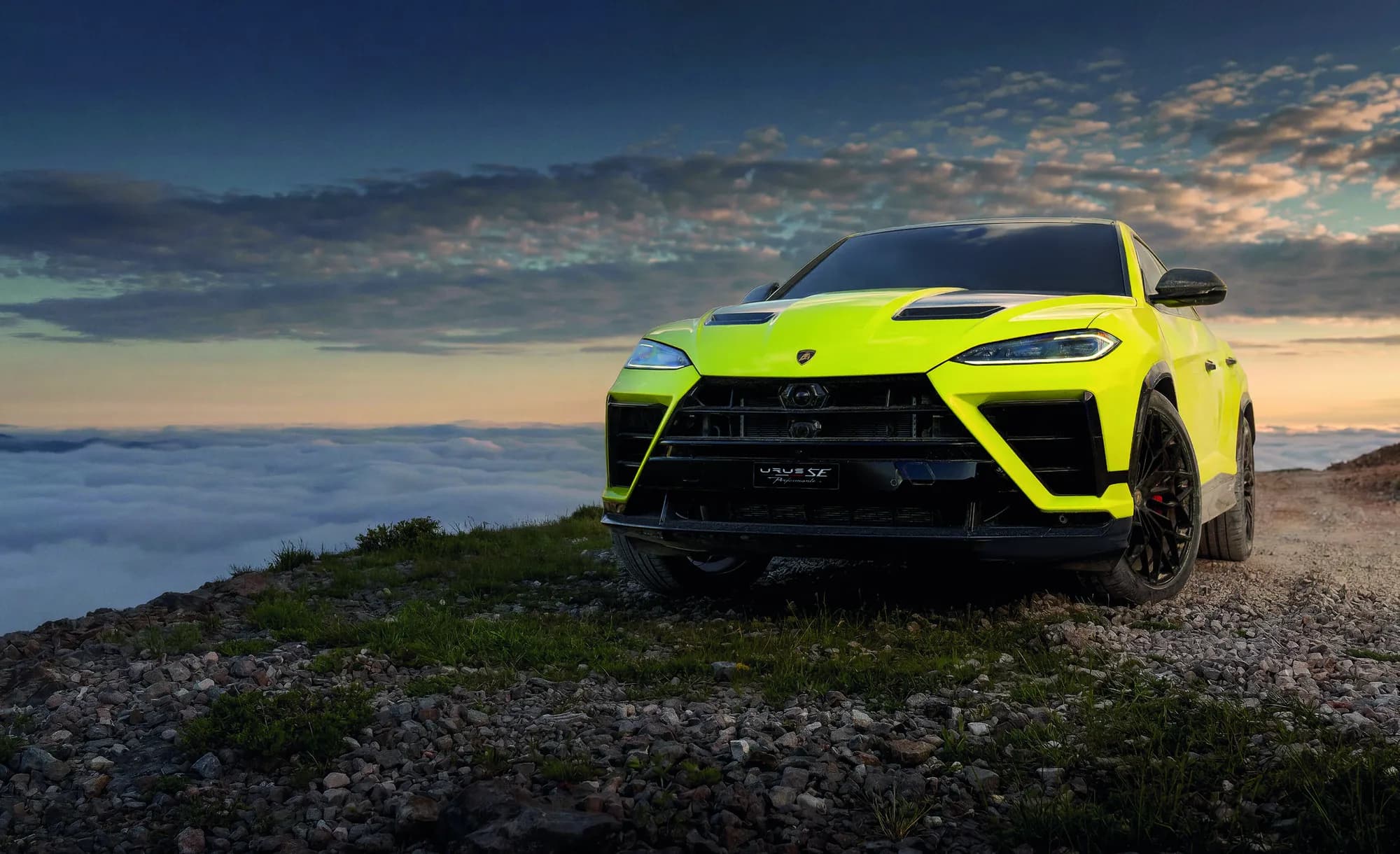 Yellow Lamborghini Urus SE Performante in front three-quarter view on a rocky mountaintop at sunset