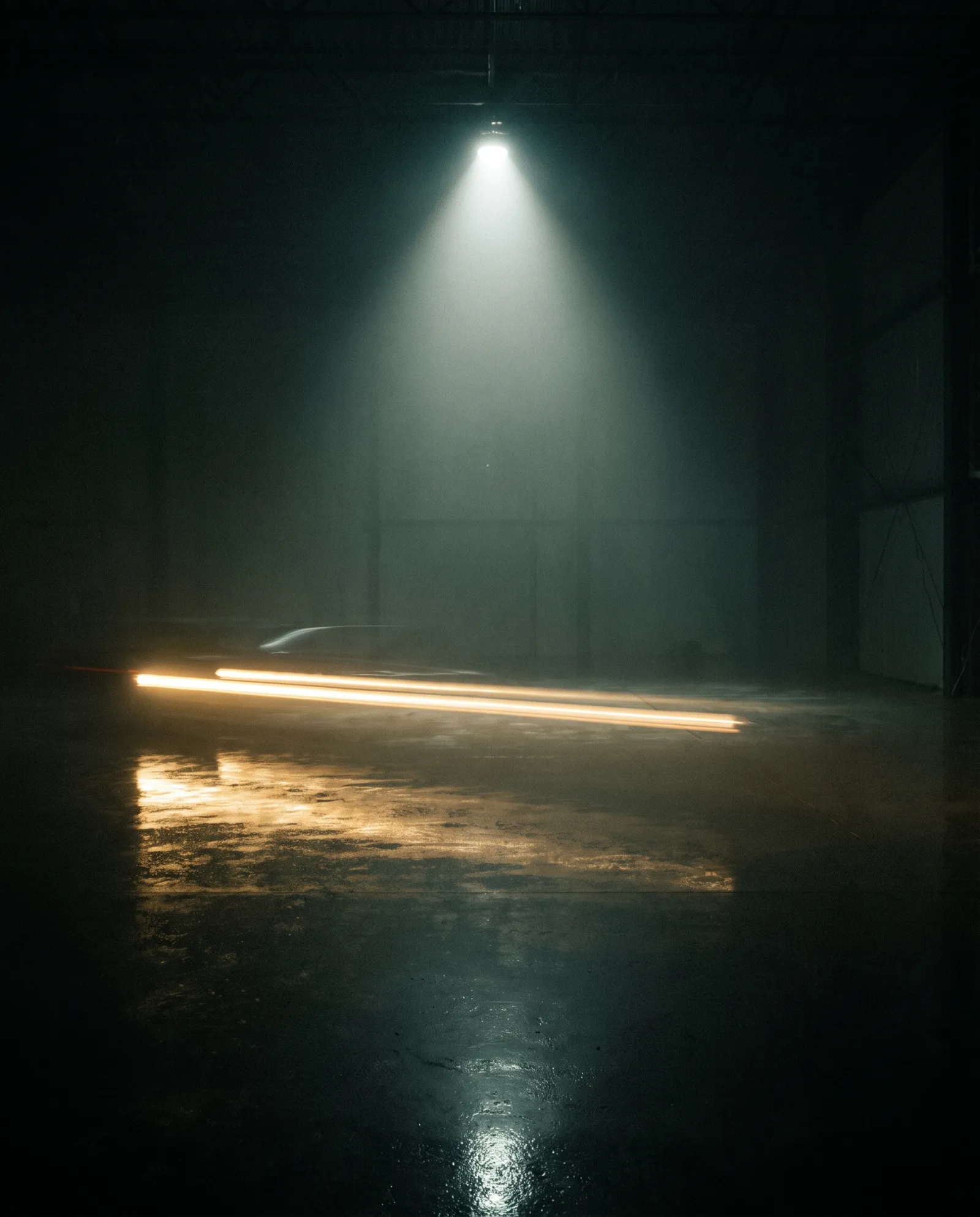 A single spotlight cutting through haze onto a dark polished floor, streaks of warm light passing low across it