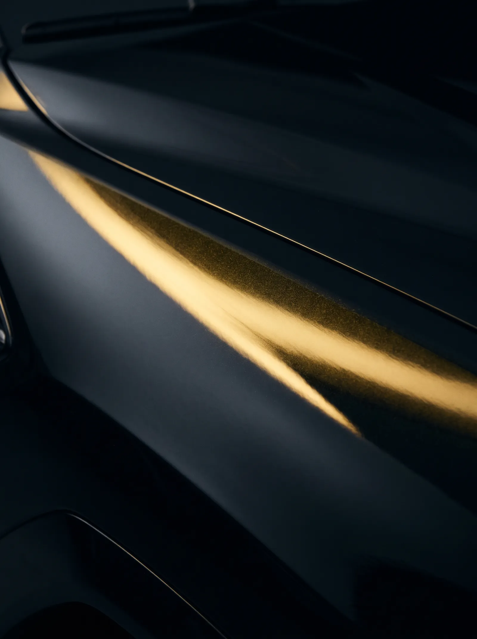 A single stripe of warm yellow light sweeping across dark, glossy car bodywork like a brushstroke