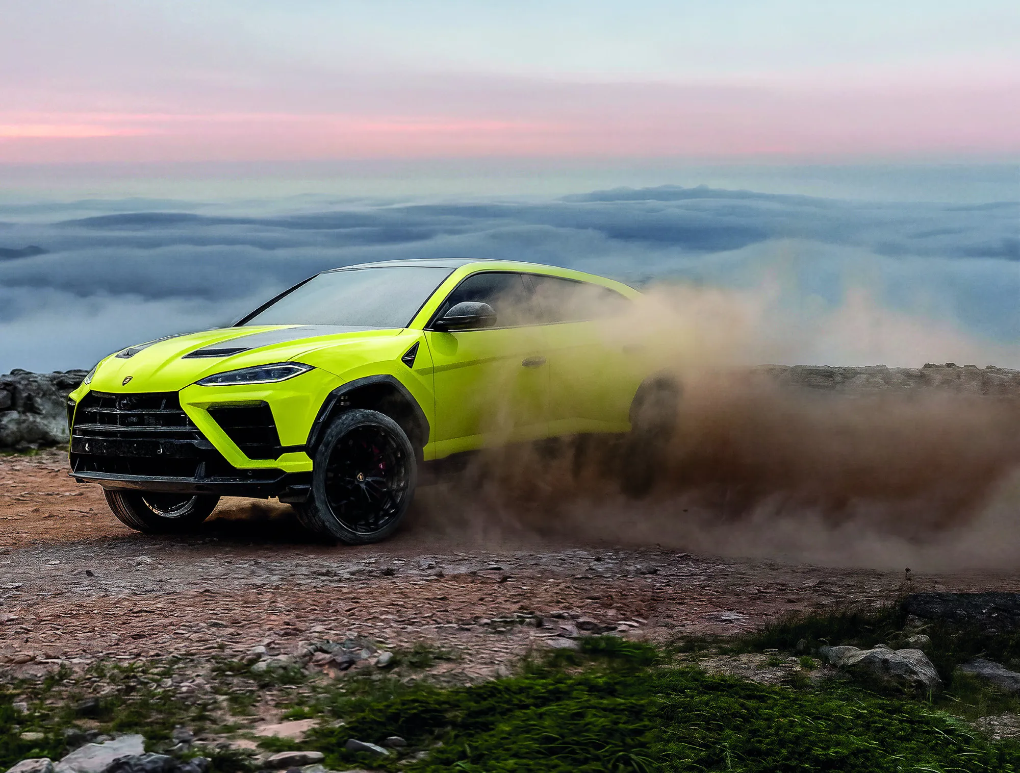 Yellow Urus SE Performante sliding across a rocky mountaintop with dust behind it